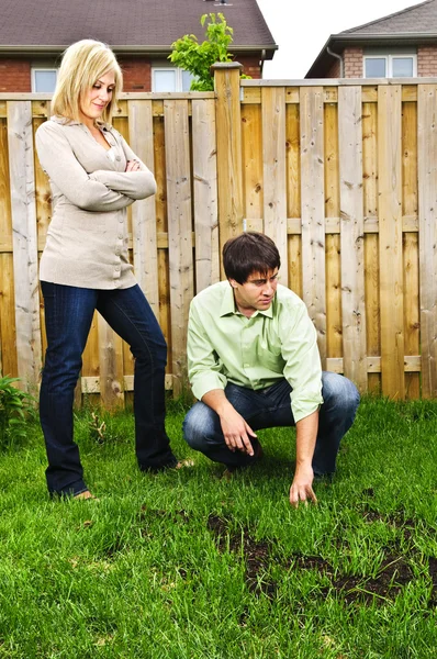 年轻夫妇担心不断增长的新家的后院的草坪 — 图库照片