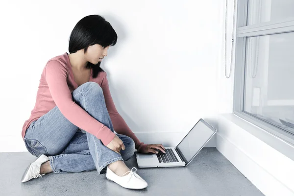 Junge Frau benutzt Laptop auf dem Fußboden — Stockfoto