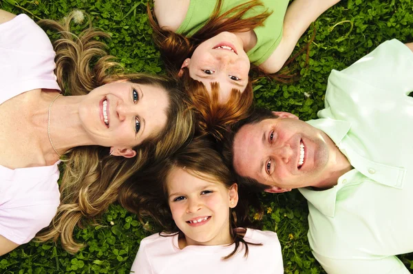 一緒に頭を探している草の上に敷設幸せな家族の肖像画 — ストック写真