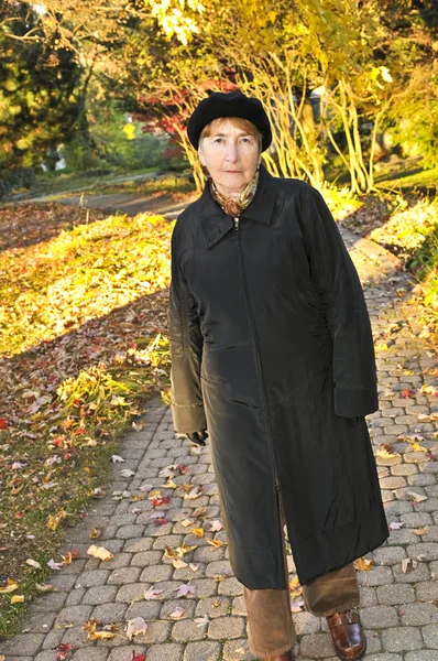 秋の公園で単独で歩いて年配の女性 — ストック写真