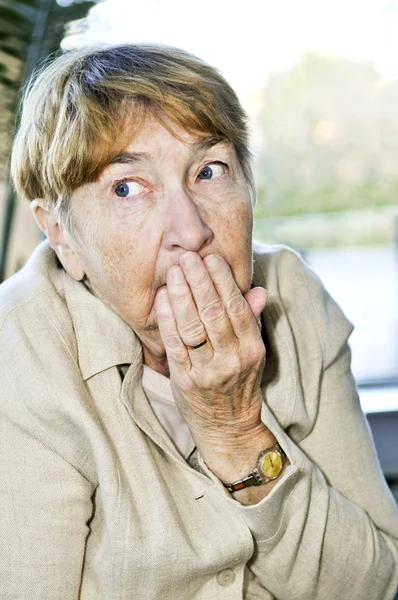 Afraid elderly woman looking sideways in fear