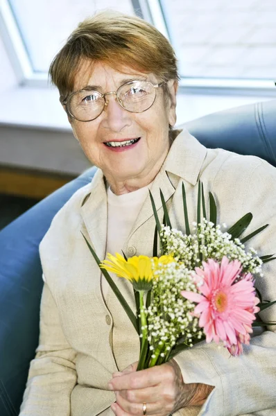 Starsza Kobieta Okularach Gospodarstwa Kwiaty Uśmiechając Się — Zdjęcie stockowe