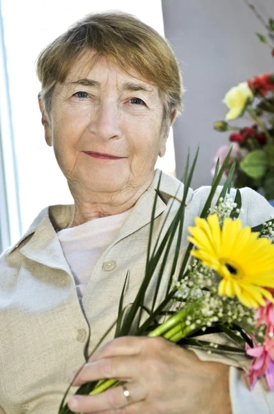 Starsza kobieta z kwiatami — Zdjęcie stockowe
