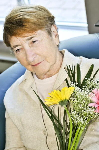 Mulher idosa triste com flores — Fotografia de Stock