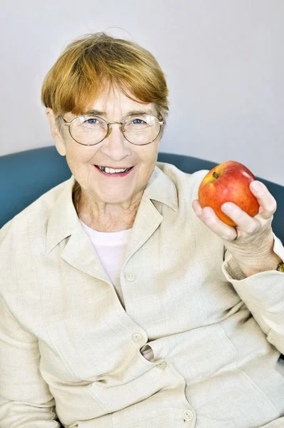 Elderly woman with apple — Stock Photo, Image