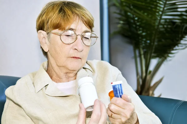 Ηλικιωμένη γυναίκα ανάγνωση χάπι μπουκάλια — Φωτογραφία Αρχείου