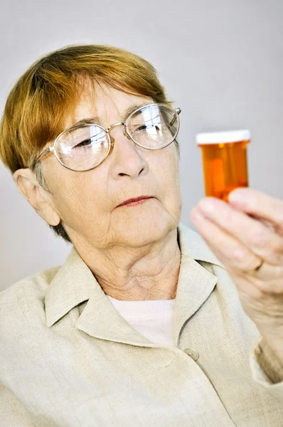 Ältere Frau Liest Warnhinweise Auf Tablettenflaschen Mit Medikamenten — Stockfoto