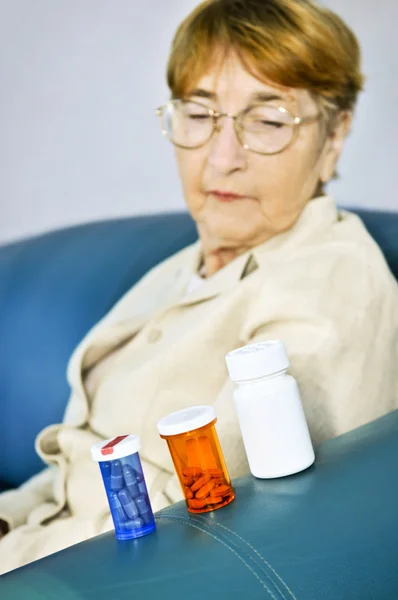 Mulher idosa olhando para garrafas de pílula — Fotografia de Stock