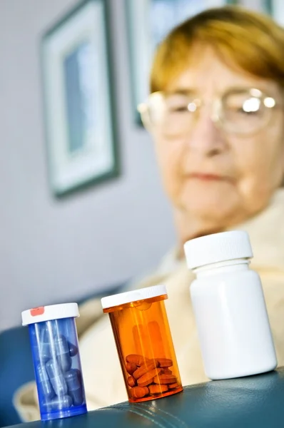 Пожилая женщина смотрит на бутылки с таблетками — стоковое фото