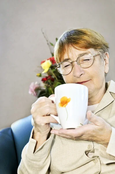 Ηλικιωμένη Γυναίκα Κάθεται Και Χαλάρωση Φλιτζάνι Τσάι紅茶のカップで座っている悲しい高齢女性 — Φωτογραφία Αρχείου