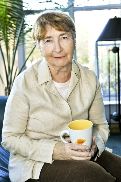 Starszy Kobieta Siedzi Uśmiechając Się Szczęśliwie Filiżanką Herbaty — Zdjęcie stockowe