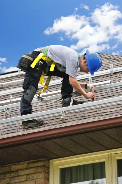 Mann arbeitet auf Dach und installiert Schienen für Sonnenkollektoren — Stockfoto