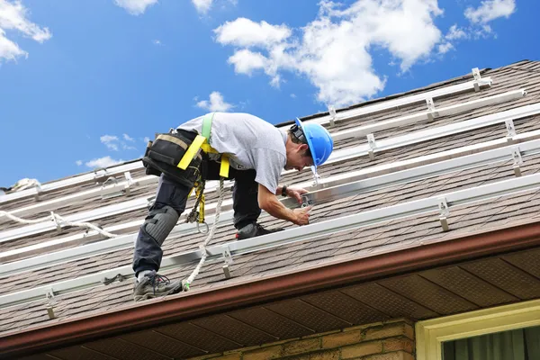 Людина працює на даху встановлюючи рейки для сонячних панелей — стокове фото