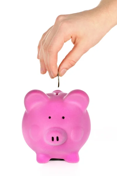 stock image Hand putting coin into pink piggy bank slot