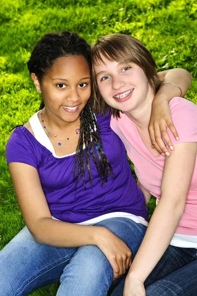 两个十几岁的女孩坐在草地上和拥抱 — 图库照片