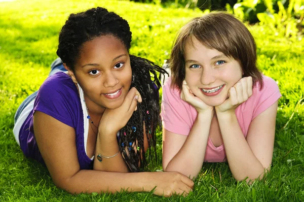 两个十几岁的女孩躺在草伸胳膊 — Stockfoto
