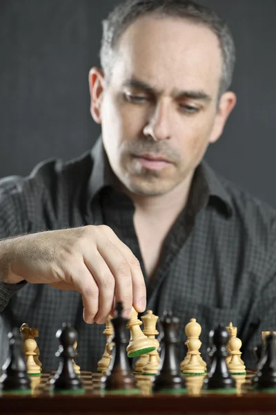 作为第一次移动的木制棋盘上移动一个象棋棋子的男人 — 图库照片