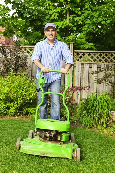 手入れの行き届いた裏庭の芝生芝刈り機を持つ男 — ストック写真