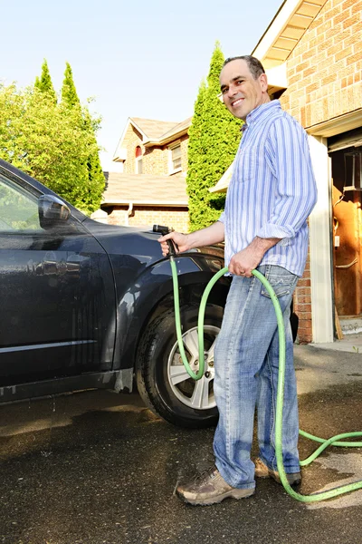 Мужчина моет машину на дороге — стоковое фото