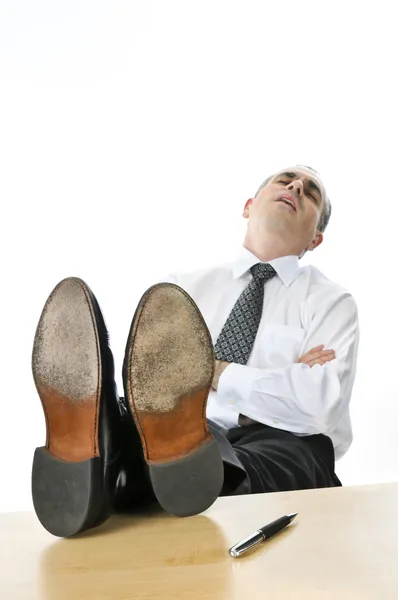 在他的办公桌上了睡觉与脚的商人 — 图库照片