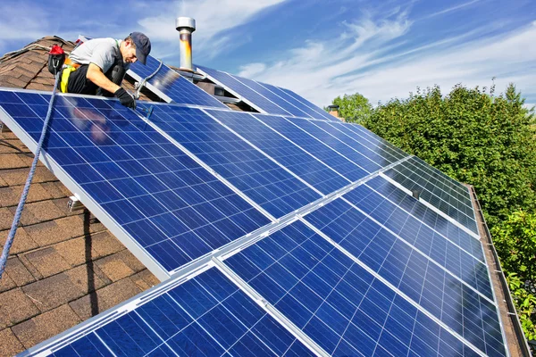 人在屋顶上安装替代能源光伏太阳能电池板 免版税图库图片