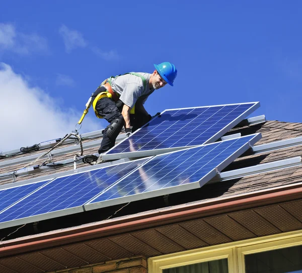 代替エネルギー太陽光発電太陽電池パネルをインストールする屋根の上の男 ロイヤリティフリーのストック画像