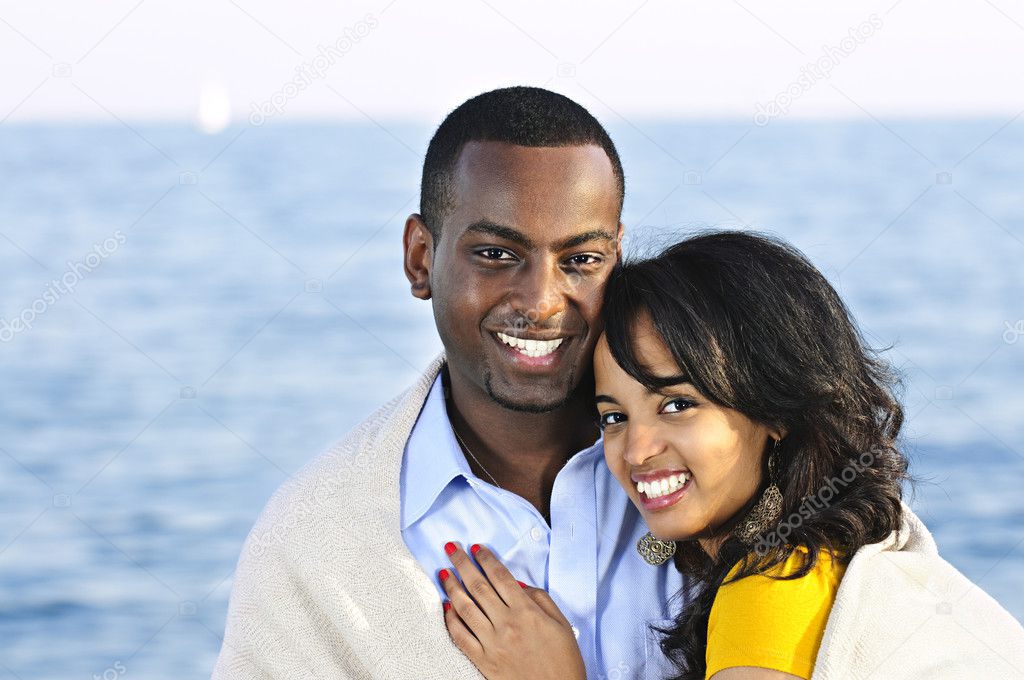 Young romantic sharing a blanket by the ocean
