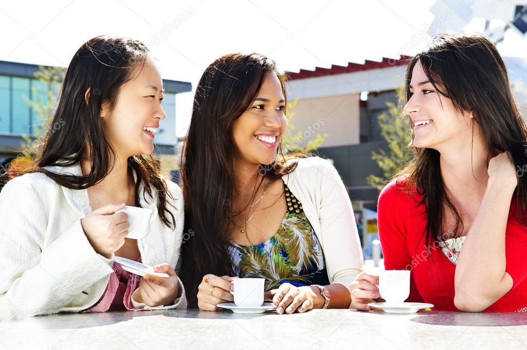 Three girl friends sitting and having drinks at outdoor mall
