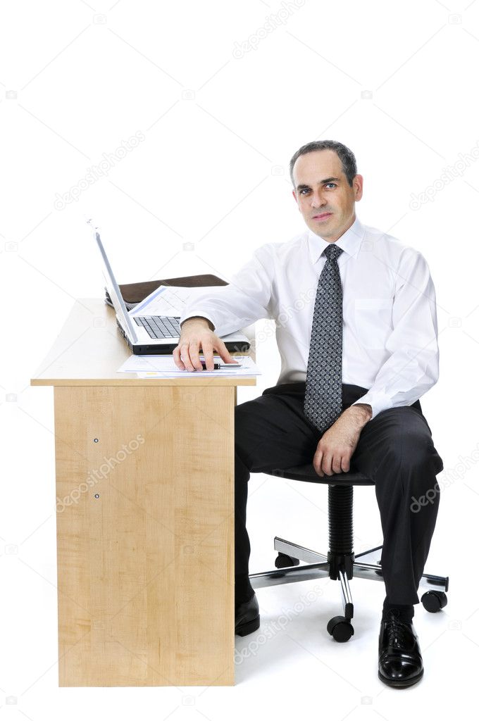 Serious businessman sitting at his desk isolated on white background