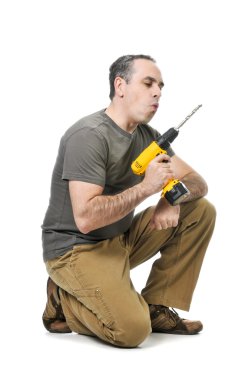 Kneeling handyman blowing on his cordless drill clipart