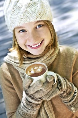 Teenage girl in winter hat with cup of hot chocolate clipart