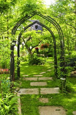 Lush green garden with wrought iron arbor clipart