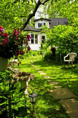 Path of steeping stones leading to a house in lush green garden clipart