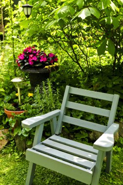 Wooden chair in a secluded corner of lush green garden clipart