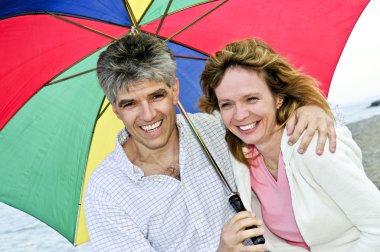 Happy mature couple with umbrella clipart