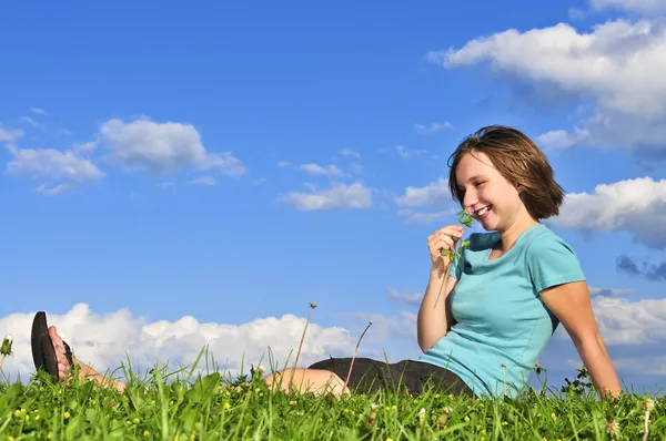 年轻的少女坐在草地上和嗅到一朵花 — 图库照片