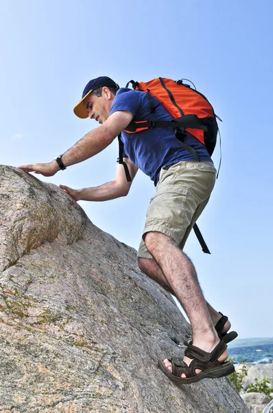 用背包爬岩石中间岁的男人 — 图库照片