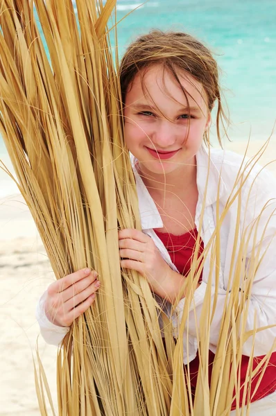 一个年轻的女孩 与棕榈树分支的热带海滩上的肖像 — 图库照片