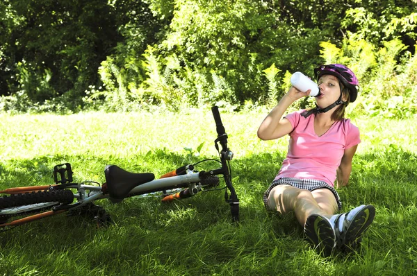 Adolescente descansando em um parque com uma bicicleta — Fotografia de Stock