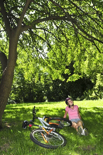 Tonårsflicka avkopplande i en park med hennes cykel — Stockfoto