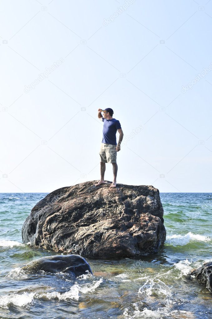Man stranded on a rock in ocean waiting for rescue