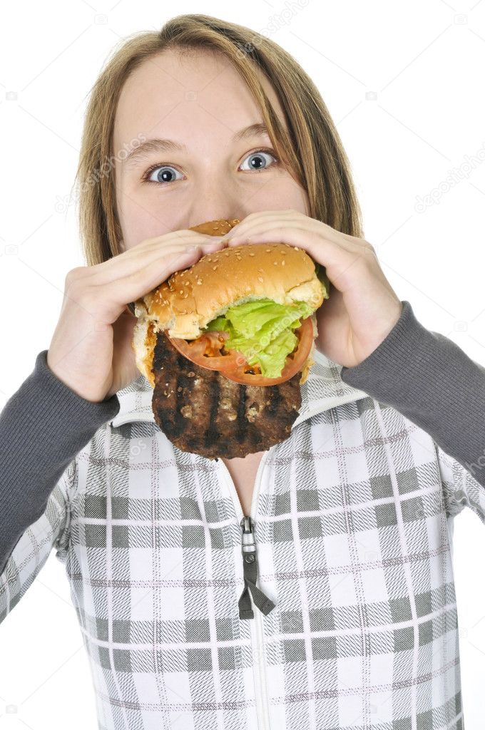 Teenage girl eating a big hamburger isolated on white background