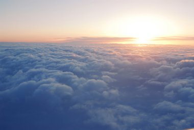 Uçak penceresinden bulutların üzerinde gün batımının muhteşem görüntüsü