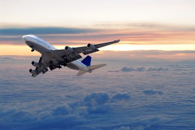 Big passenger airplane flying above the clouds and sunset clipart