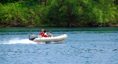 A couple driving an inflatable boat on a river clipart