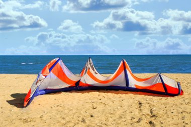 Big kite for kite surfing lying on a sandy beach clipart