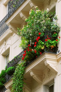 Wrought iron balcony full of flowers on historic building in Paris, France clipart