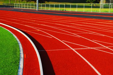 Curving lanes of a red racetrack in a stadium clipart