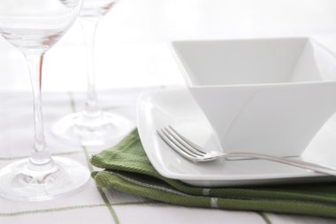 Place setting with white dishes and wine glasses clipart