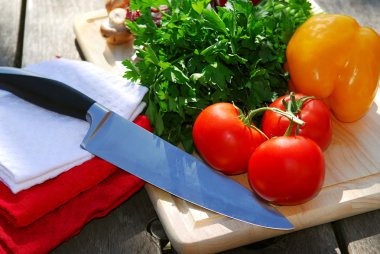 Assorted fresh vegetables on cutting board on rustic table with a chef knife clipart